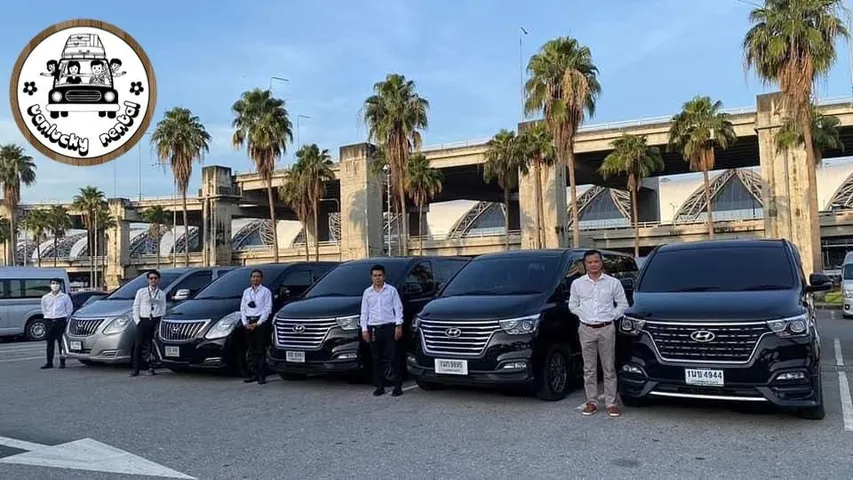 ทีมคนขับในเสื้อเชิ้ตสีขาวยืนหน้ารถตู้ Hyundai H1 ที่สนามบิน